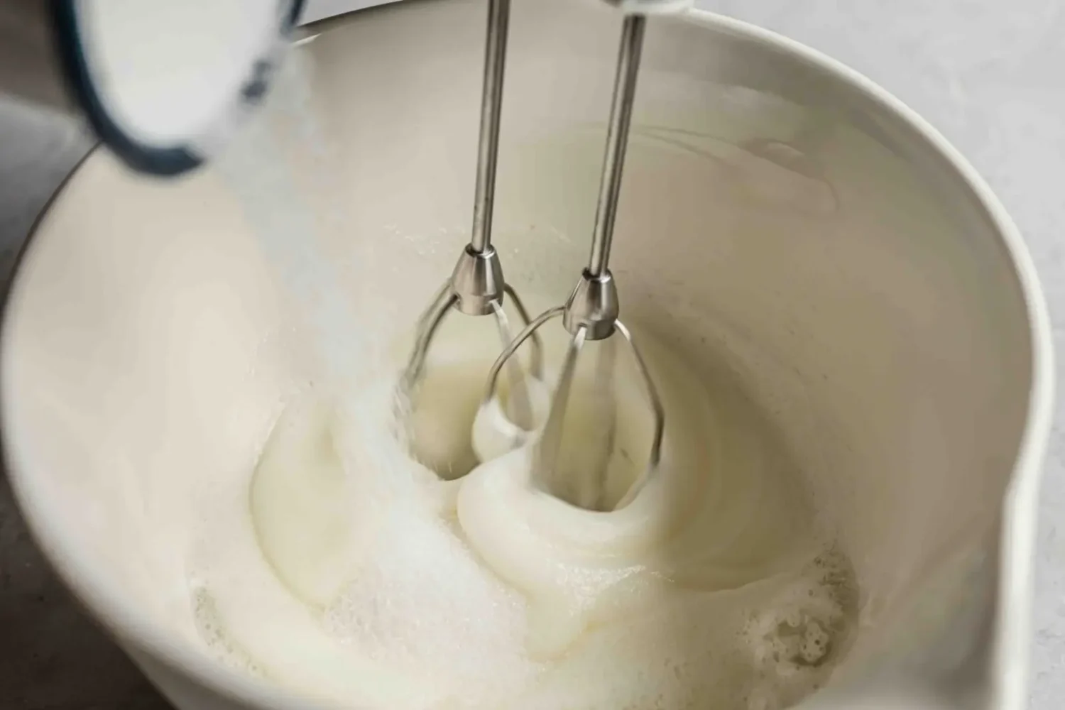 Sucre versé en pluie sur des blancs déjà mousseux